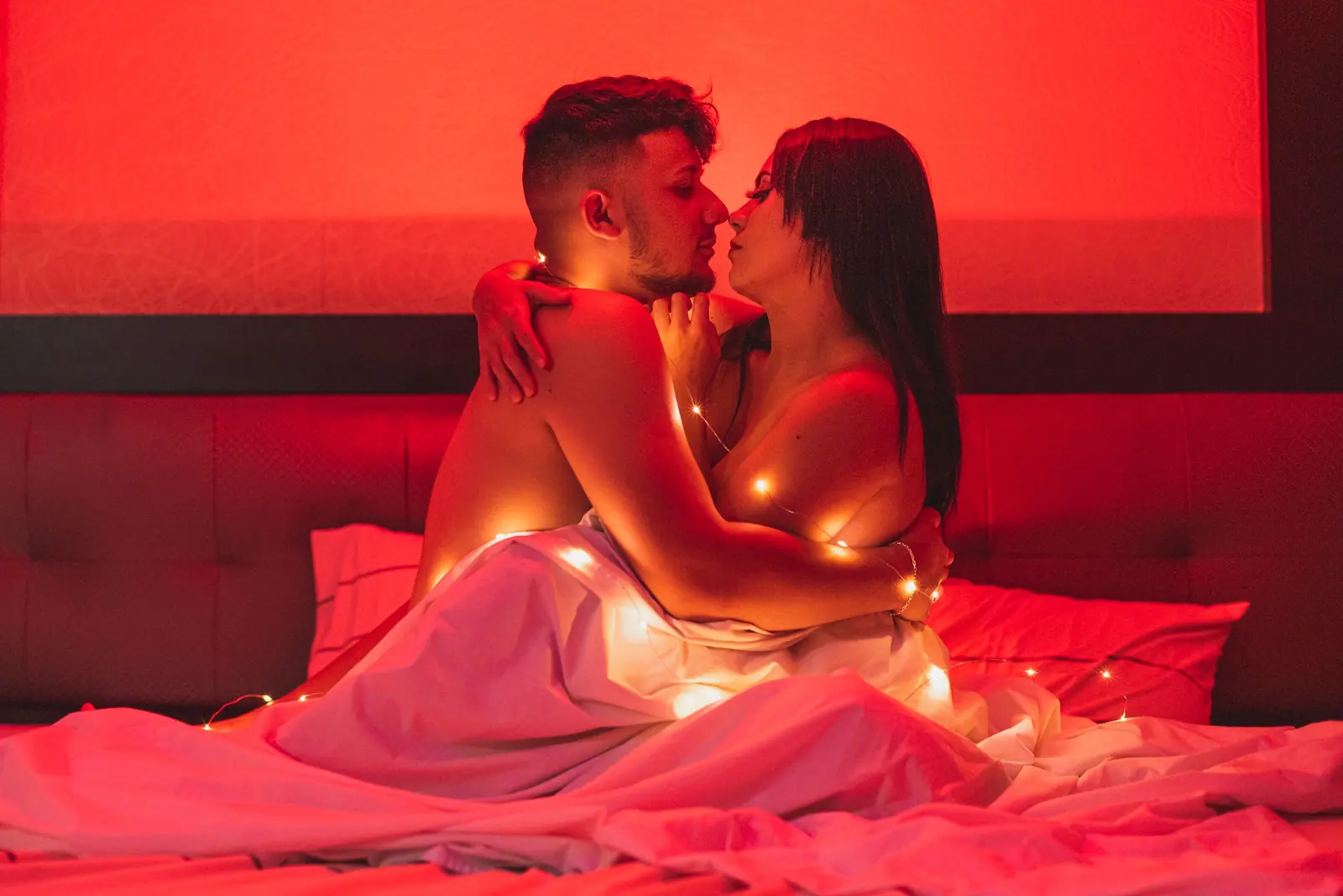 Illustrative stock image of an adult couple kissing under red lighting